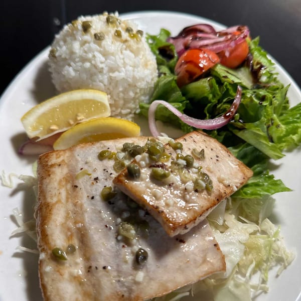Hana Hou Restaurant's grilled fish with capers, white rice, lemon slices, and a side salad.